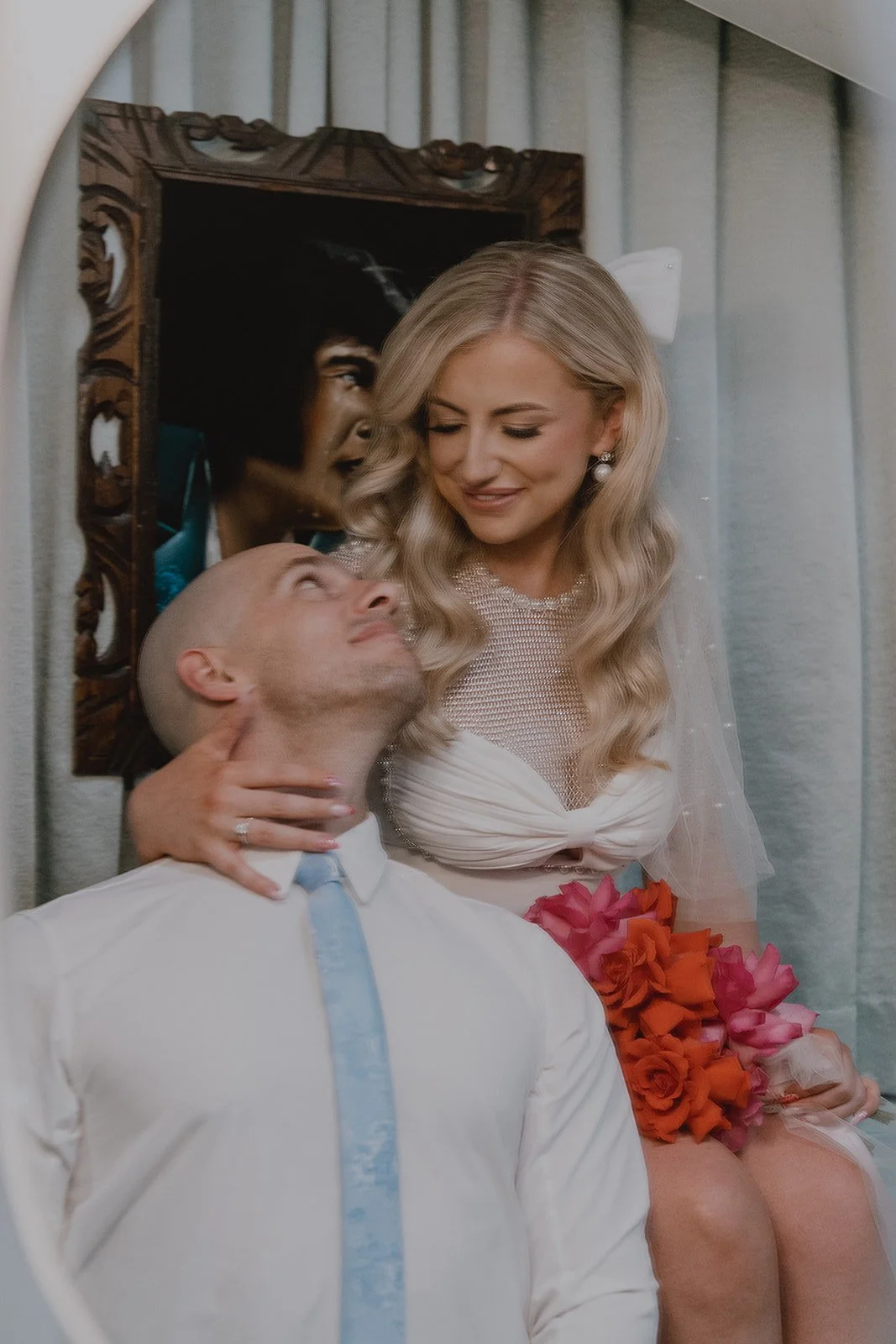 Bride leaning toward the groom while sitting on the bathroom counter at Sure Thing Chapel in Las Vegas.