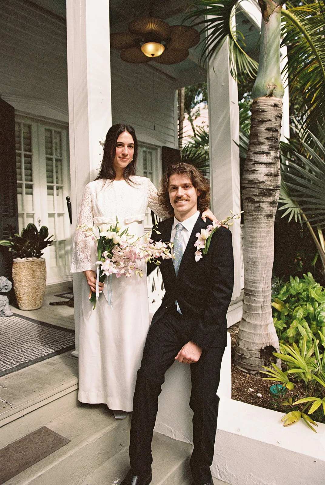 Bride and groom posing together on the steps of Old Town Manor in Key West Florida on 35mm film.