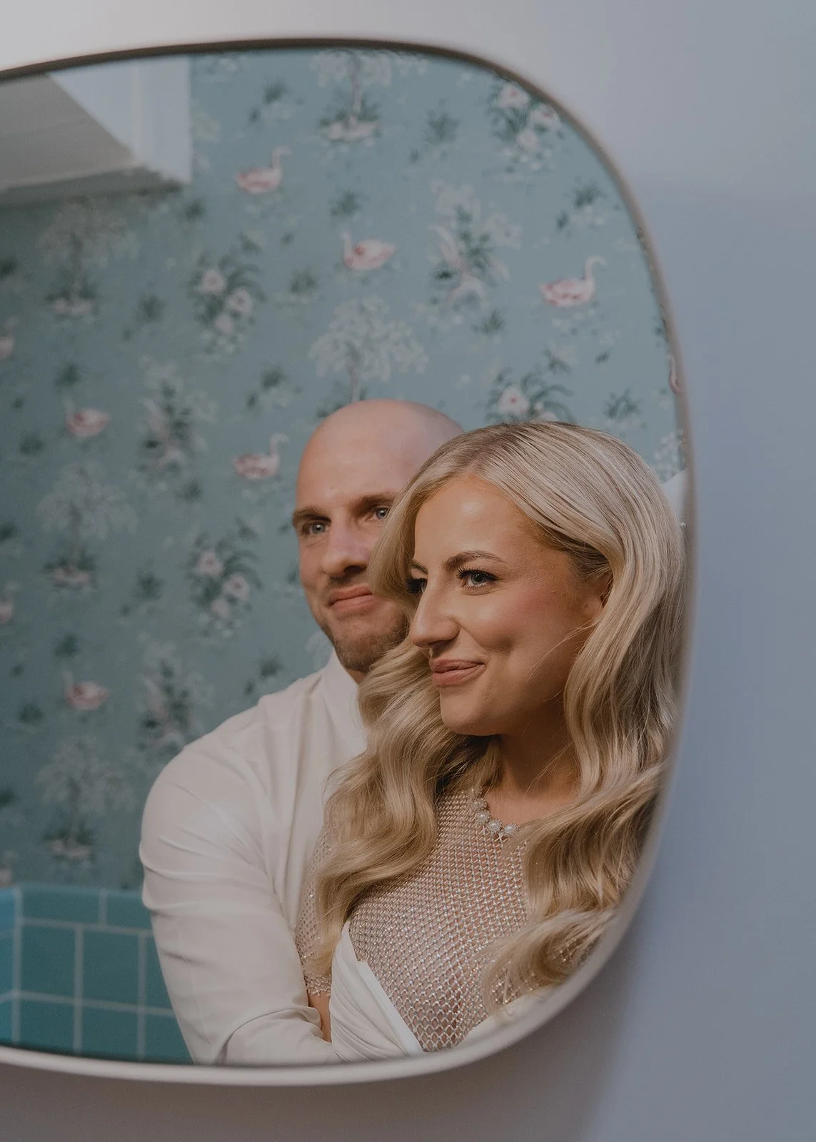 Bride and groom reflected in a bathroom mirror at Sure Thing Chapel during their Las Vegas wedding portraits.