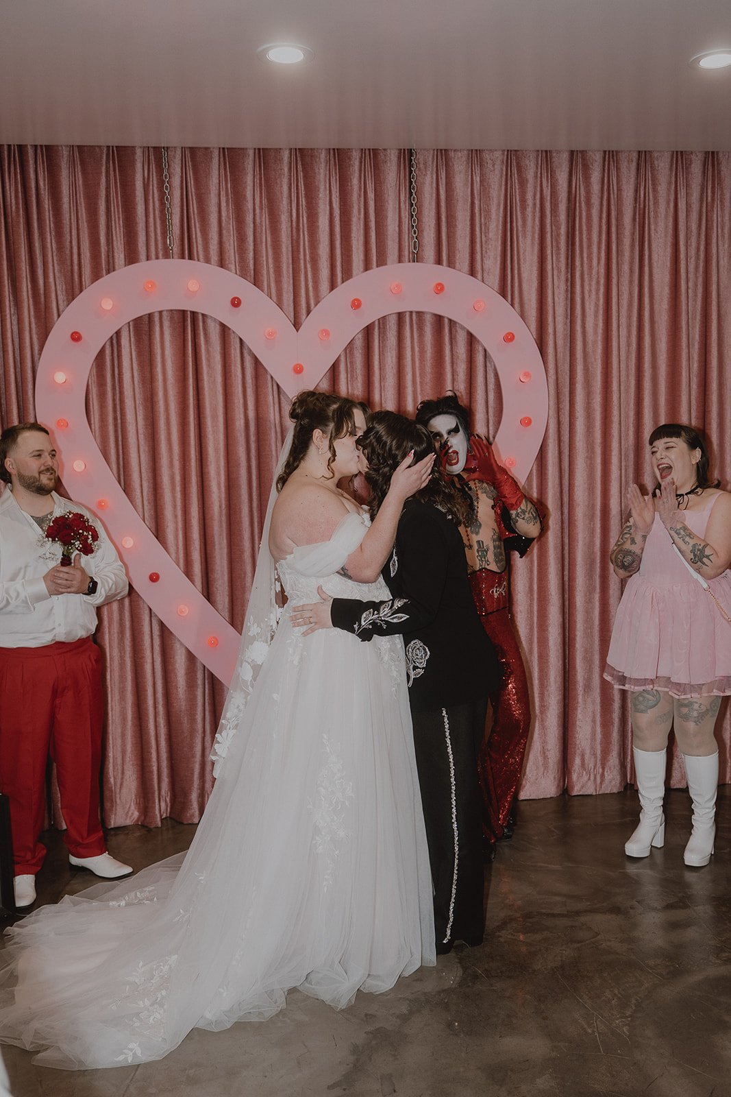 Couple kissing after their Sure Thing Chapel wedding ceremony with Hellvis and their wedding party celebrating.