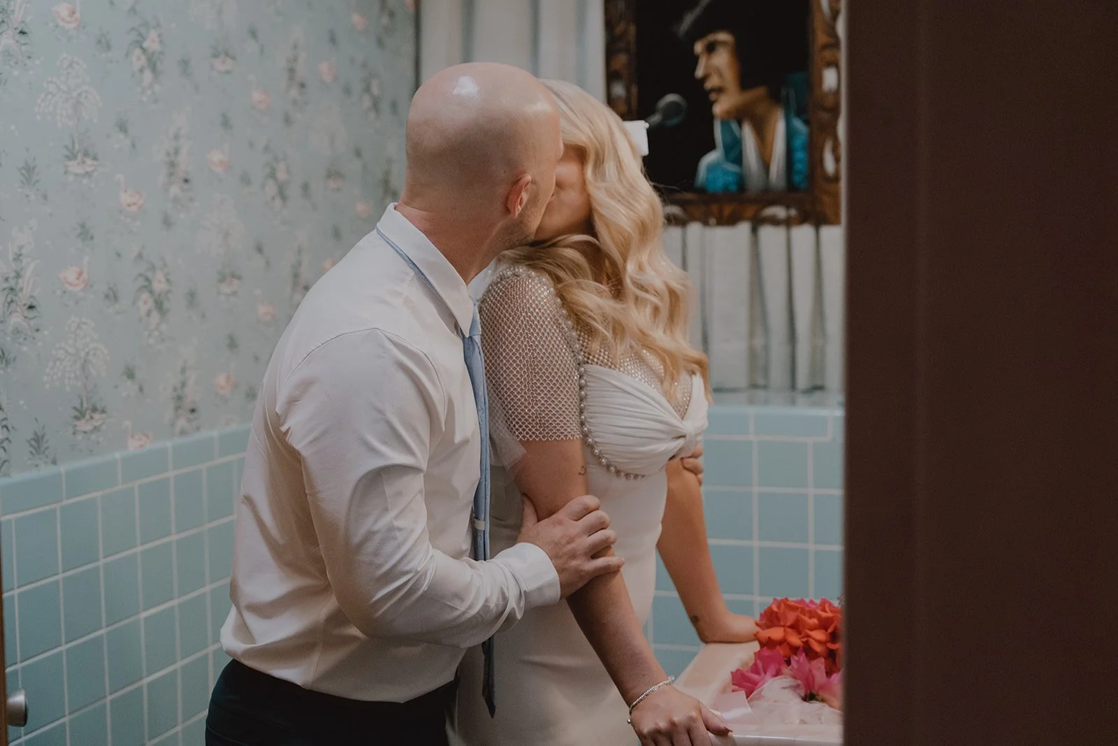 Intimate portrait of the bride and groom in the Sure Thing Chapel bathroom with vintage mirrors and tile.