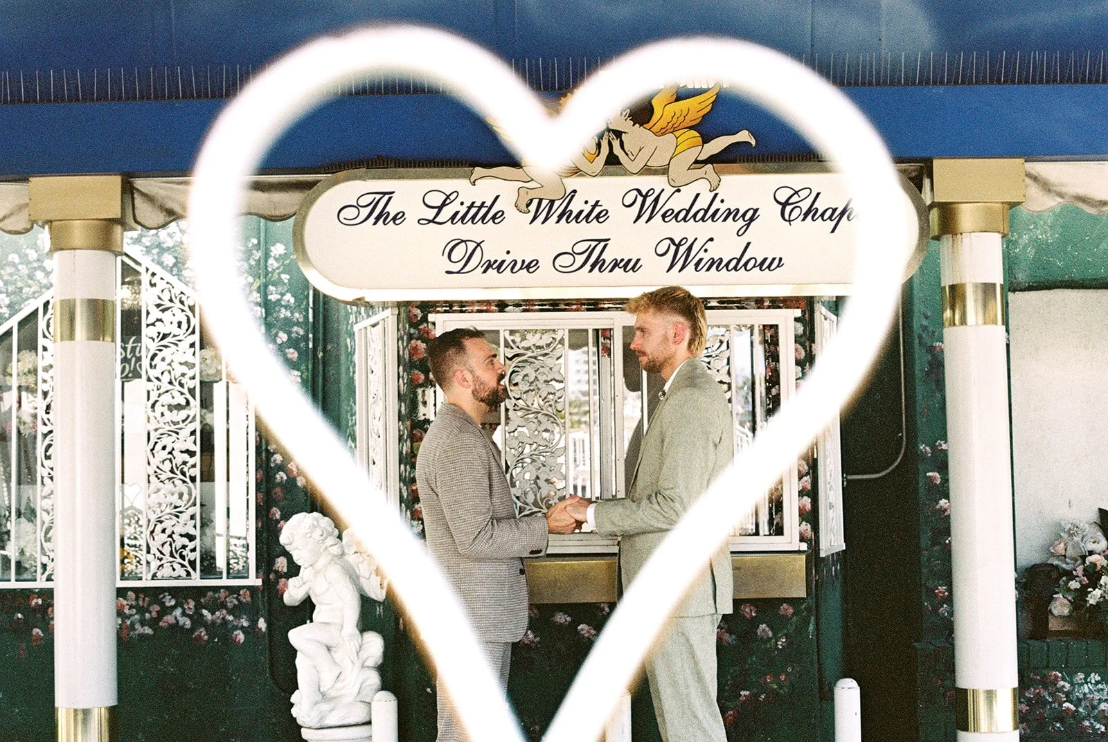 35mm film photo of a couple through hte white heart fence at a Little White Wedding Chapel in Las Vegas.