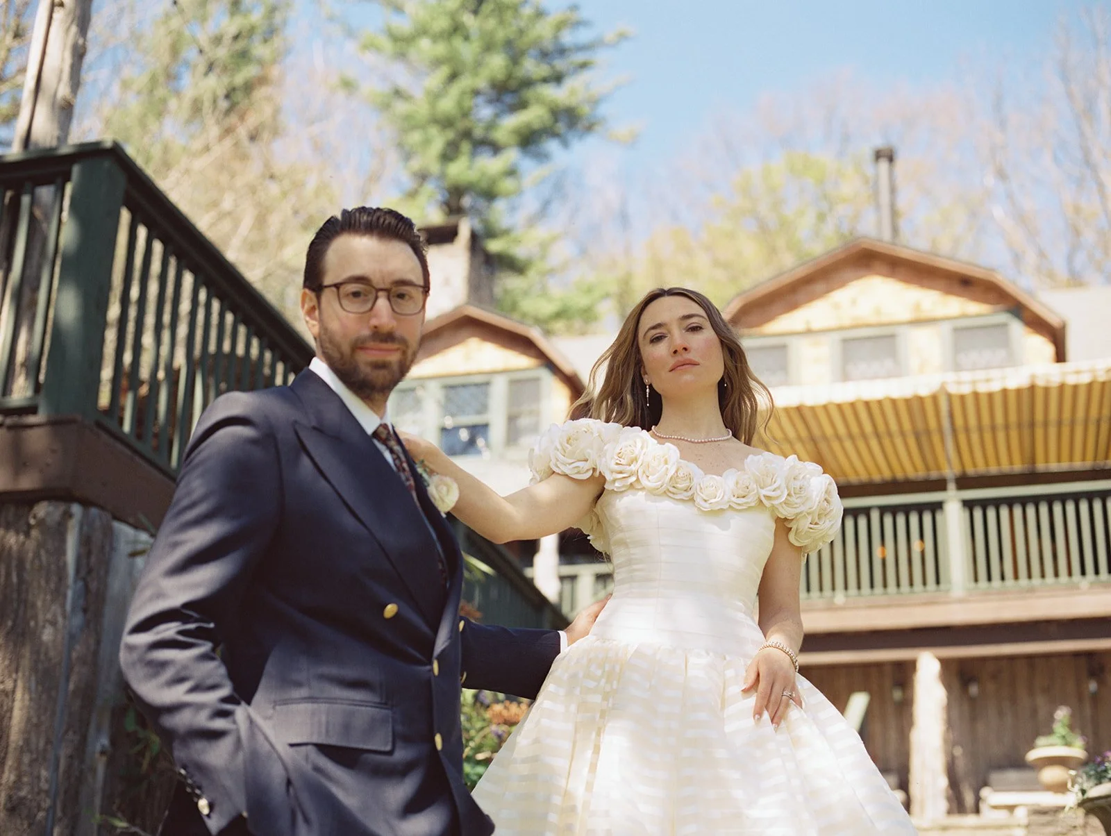 Low-angle film wedding portrait of the bride and groom posing outside Deer Mountain Inn in the Catskills.