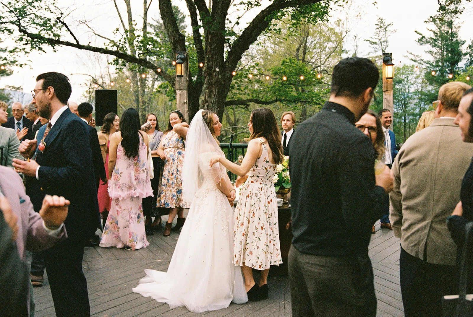 Candid film photo of the bride talking with a guest during cocktail hour on the Deer Mountain Inn terrace.