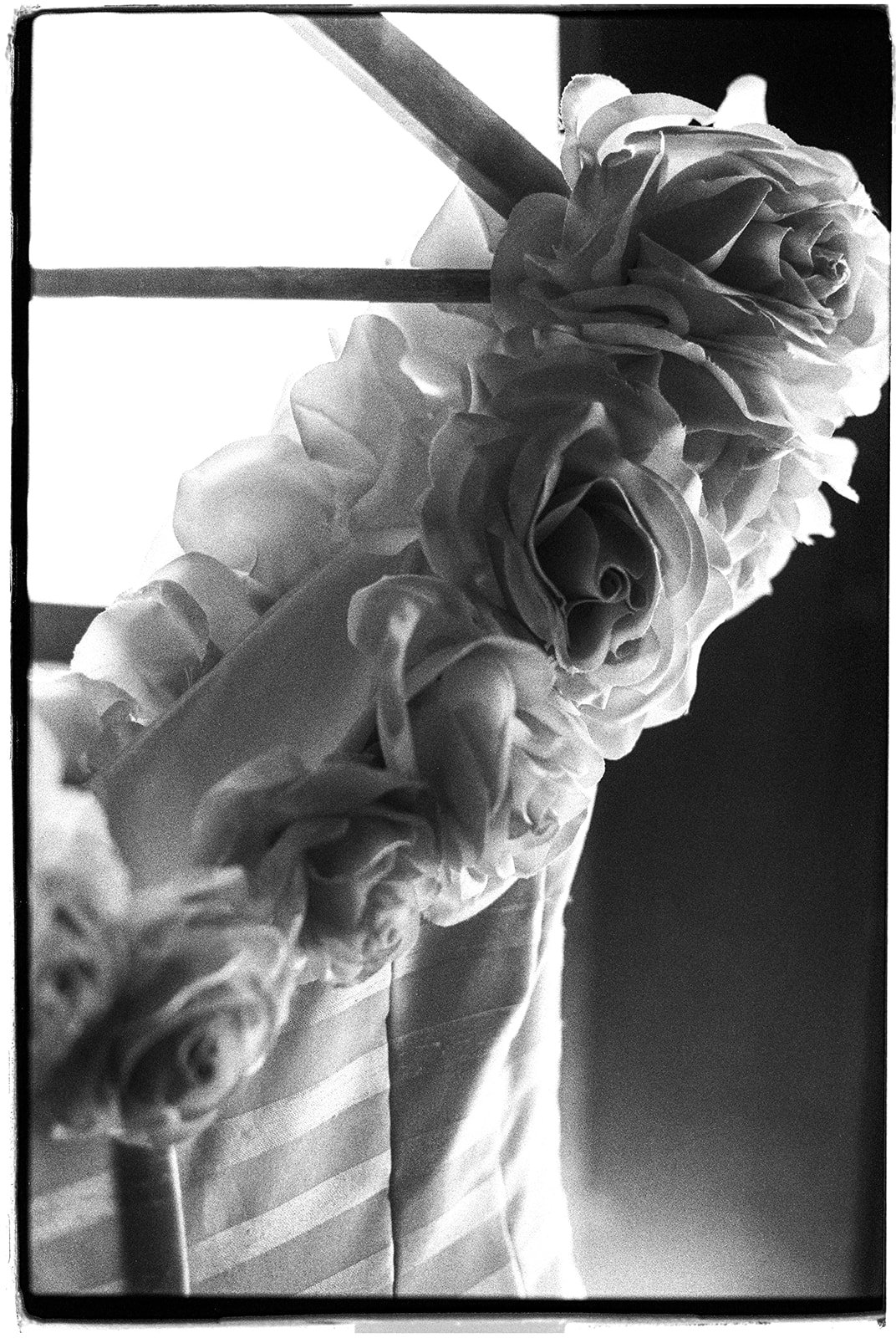 Black-and-white film photo showing the floral neckline and striped fabric of the bride’s wedding dress.