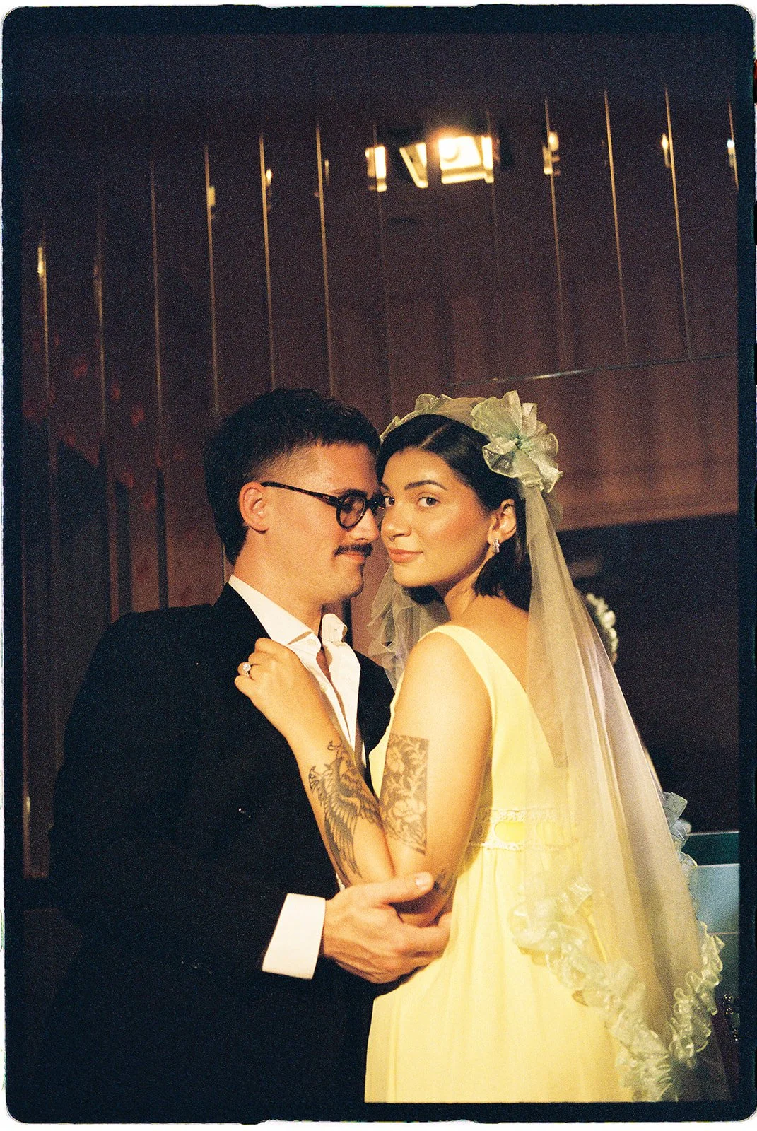Moody 35mm film portrait of a couple embracing in wedding attire against dark mirrored walls at Sure Thing NYC.
