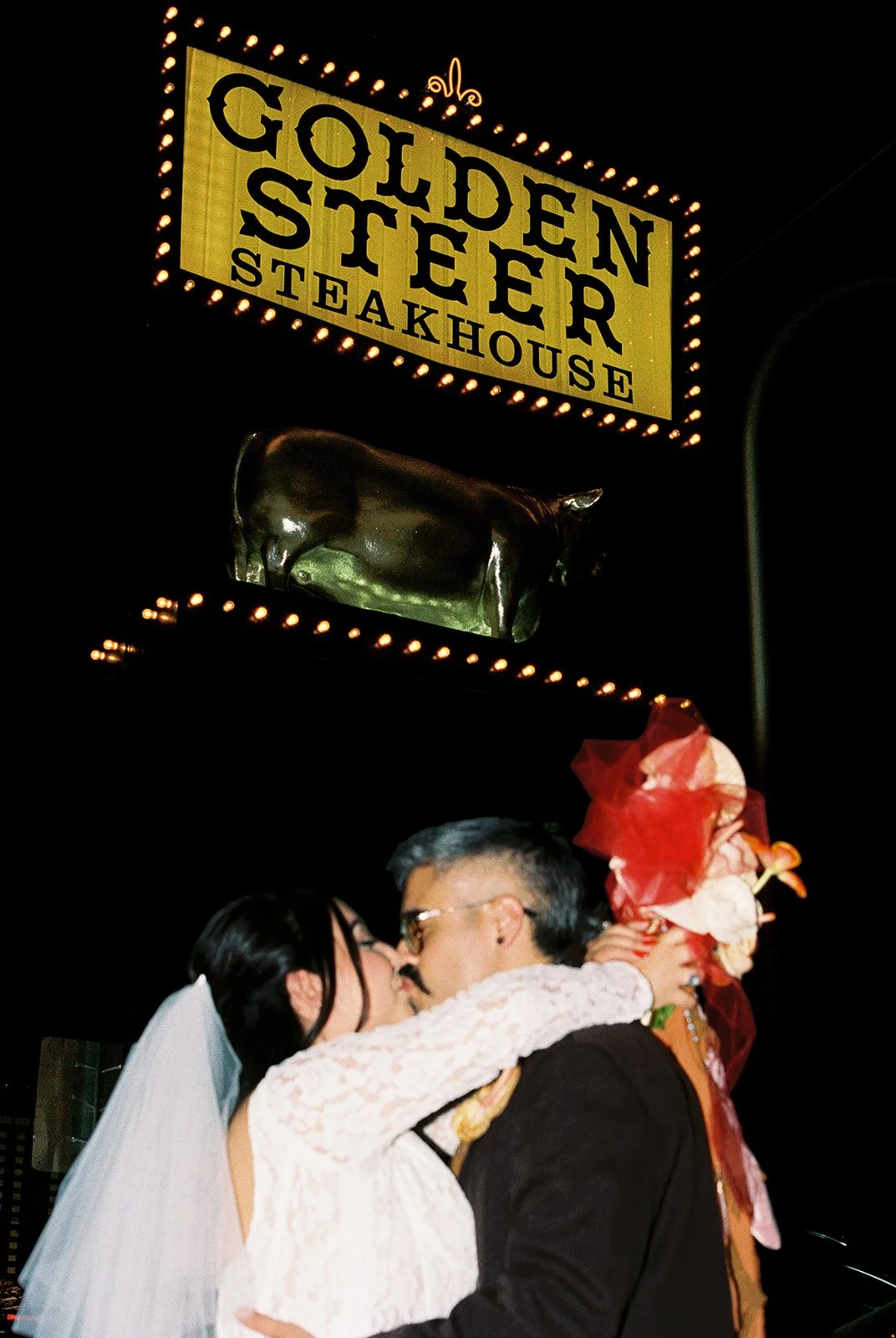 Couple kissing in front of the Golden Steer Steakhouse sign.
