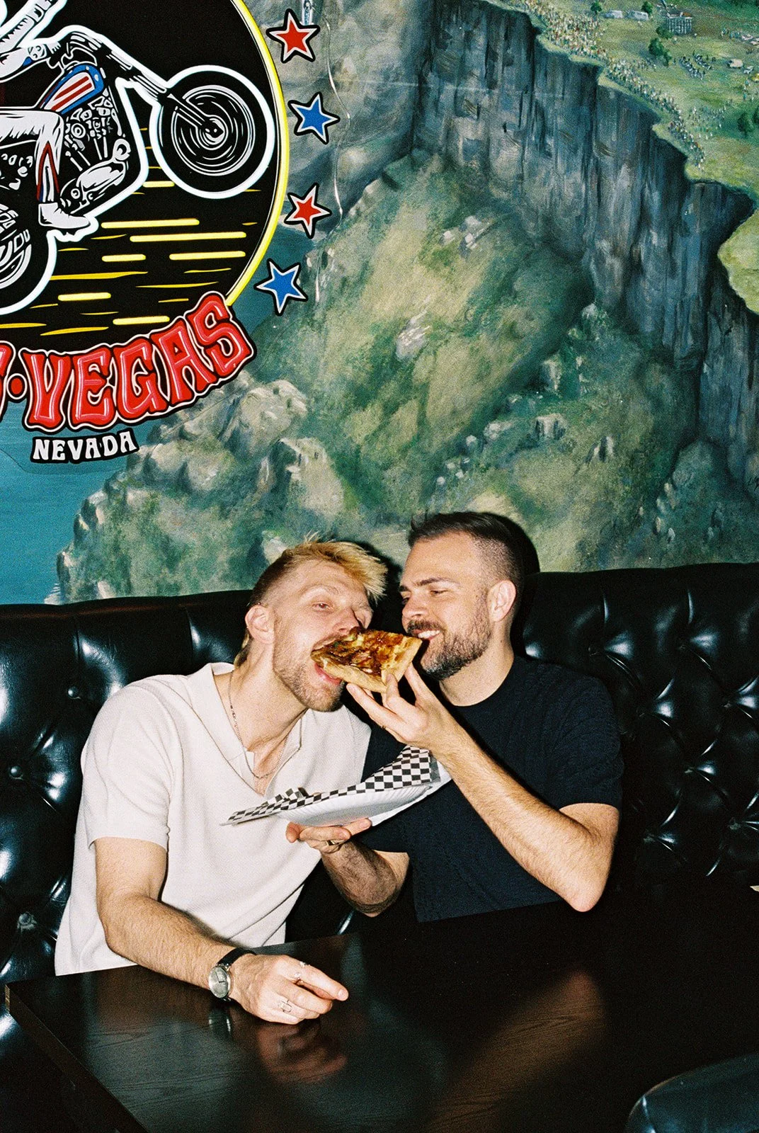 Man feeding his husband pizza at Evel Pie in Las Vegas for their elopement photos on 35mm film.