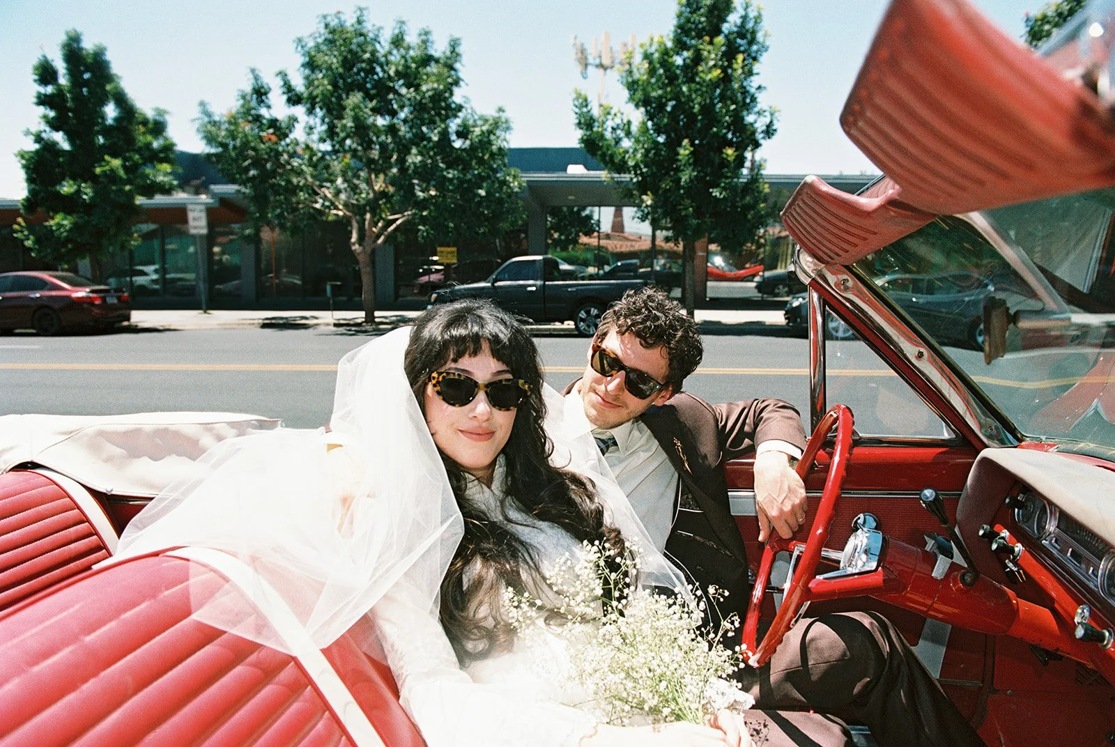Couple posing in a classic red car for their Las Vegas elopement photos.