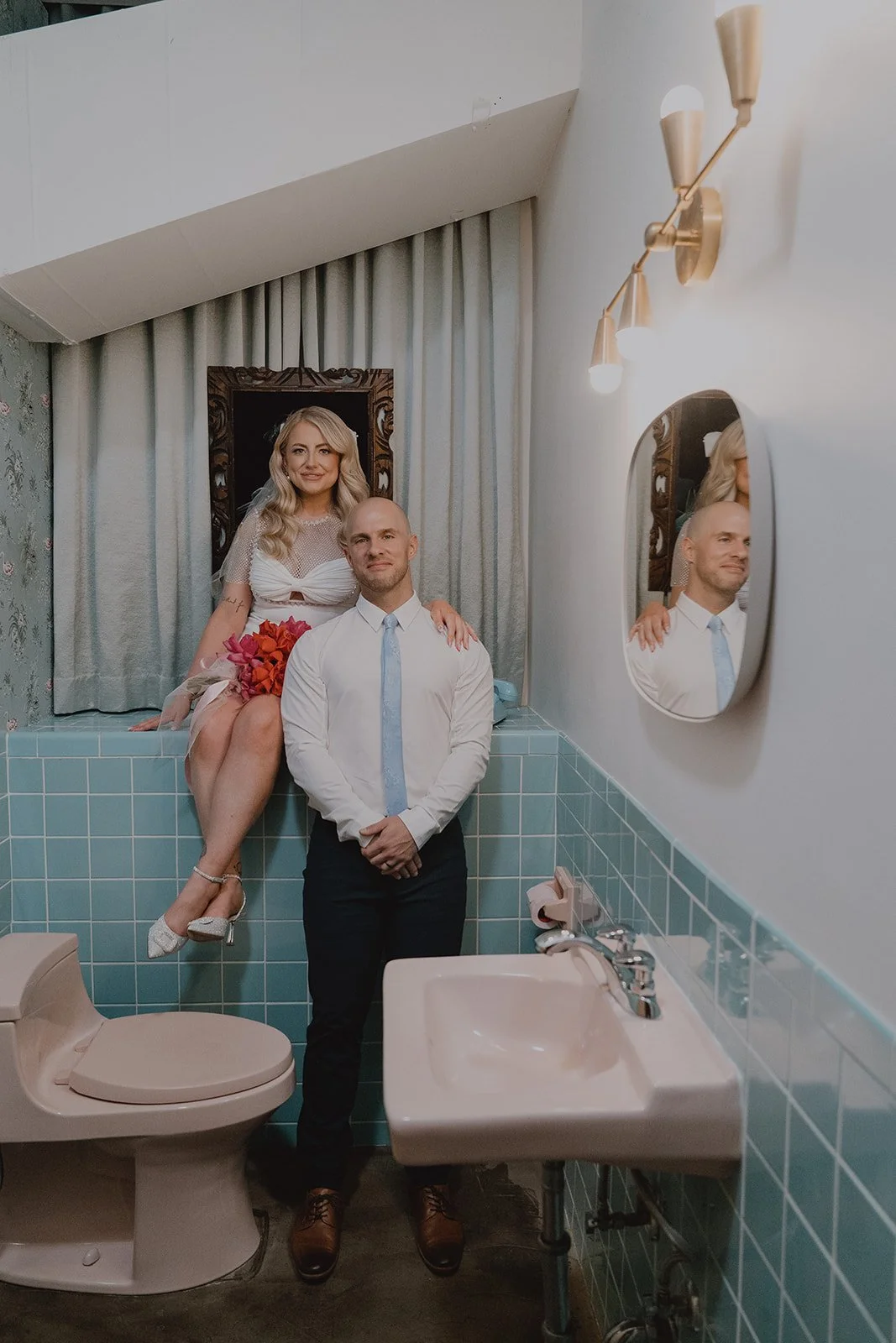 Bride and groom sitting together in the baby blue tiled bathroom at Sure Thing Chapel in Las Vegas.