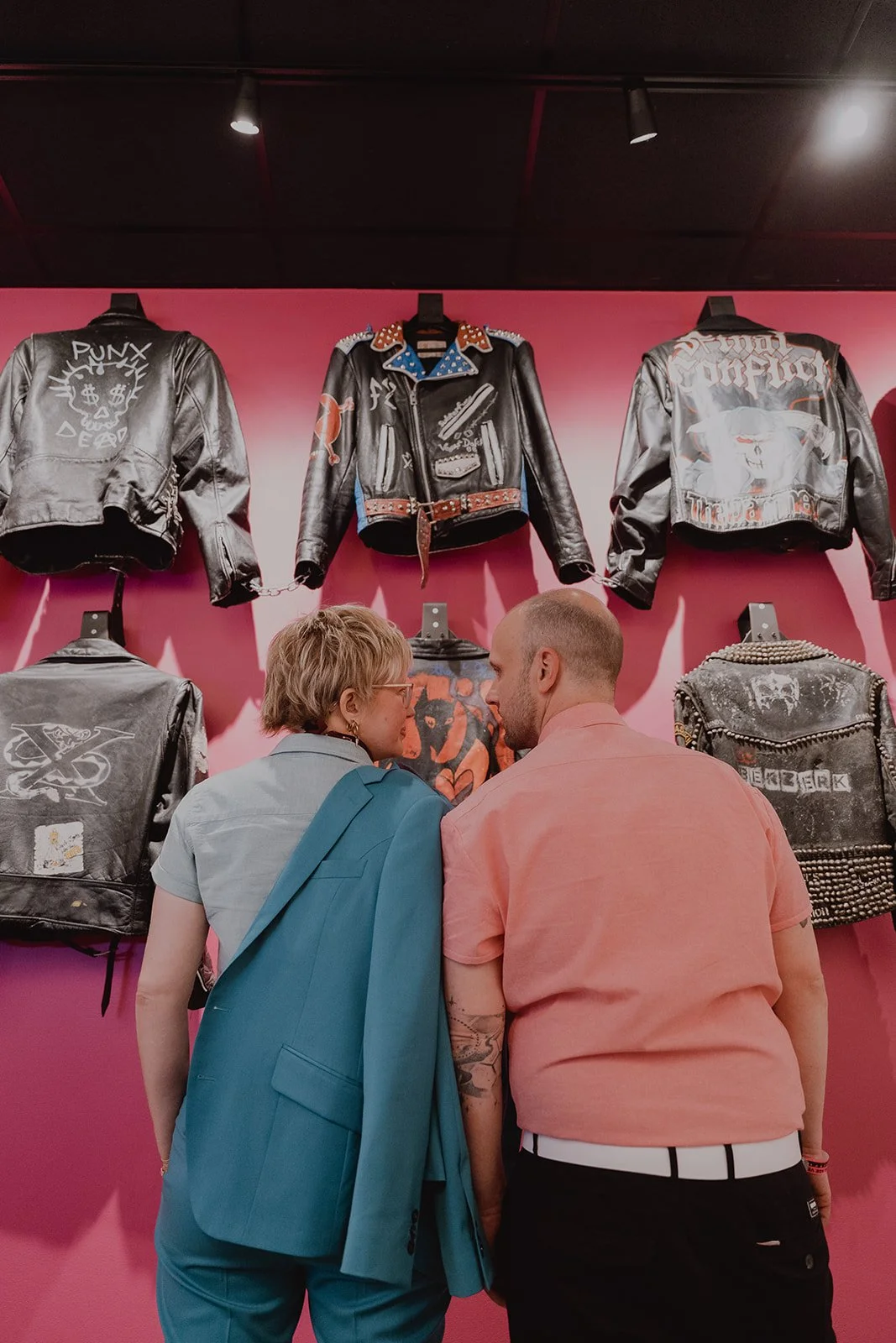 Couple posing in front of a wall of leather jackets inside The Punk Rock Museum in Las Vegas.