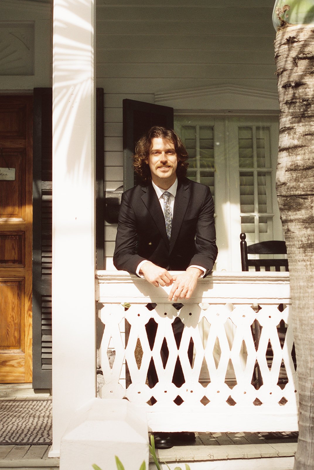 Groom standing on the porch at Old Town Manor in Key West, Florida during a 35mm film elopement.