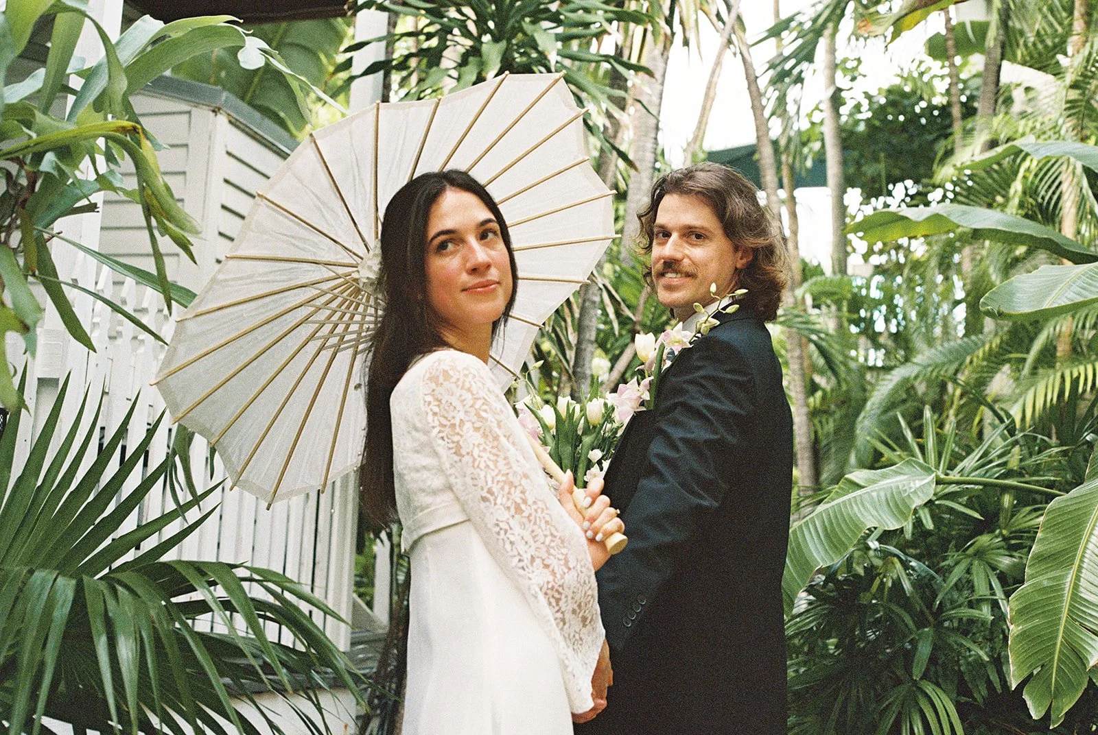 Bride and groom posing under tropical greenery at Old Town Manor in Key West during their film elopement.
