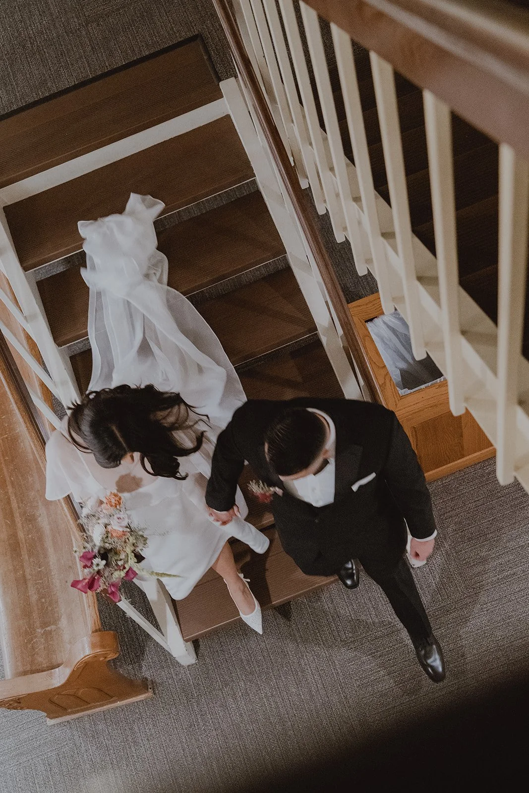 Bride and groom holding hands and walking down the stairs at Old Orange County Courthouse.