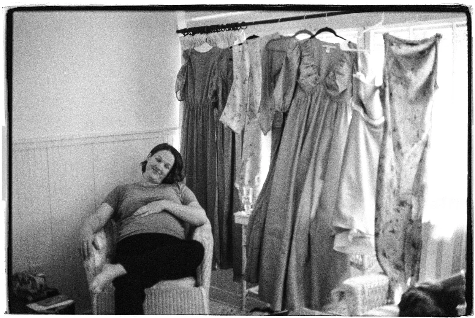 Black and white film photo of a pregnant woman resting during edding preperations.