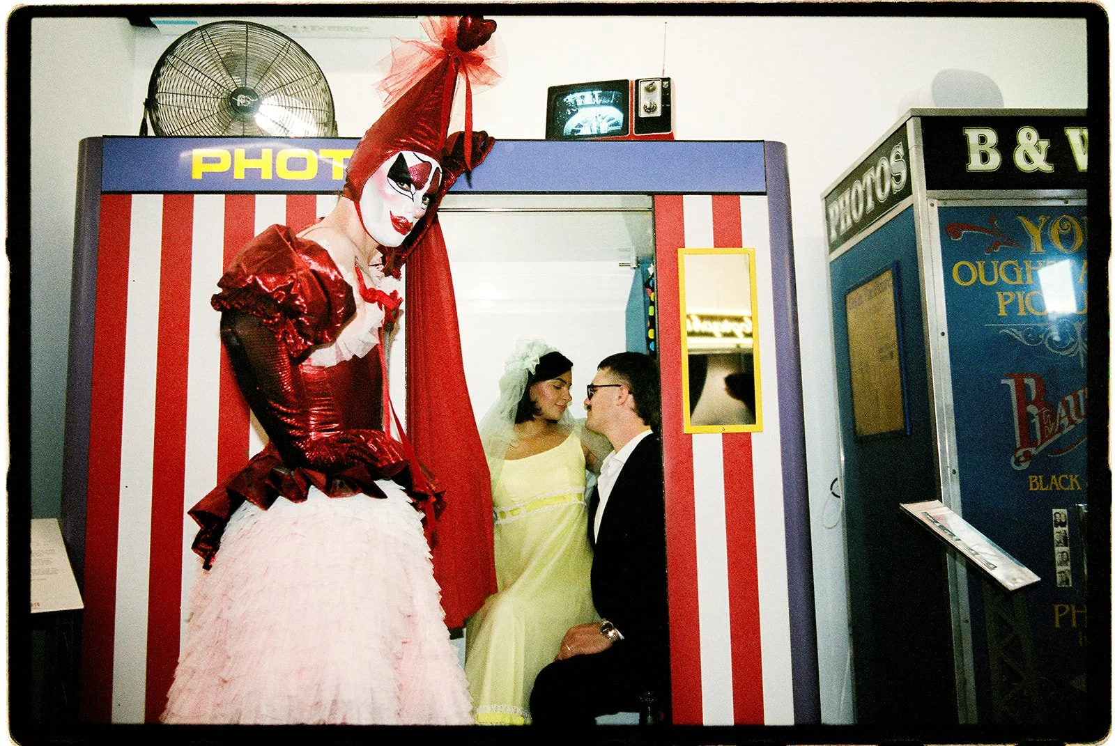 Tillie the Clown posing in front of vintage photobooths at AUTOPHOTO in New York City, wearing a red corset and layered tulle skirt.