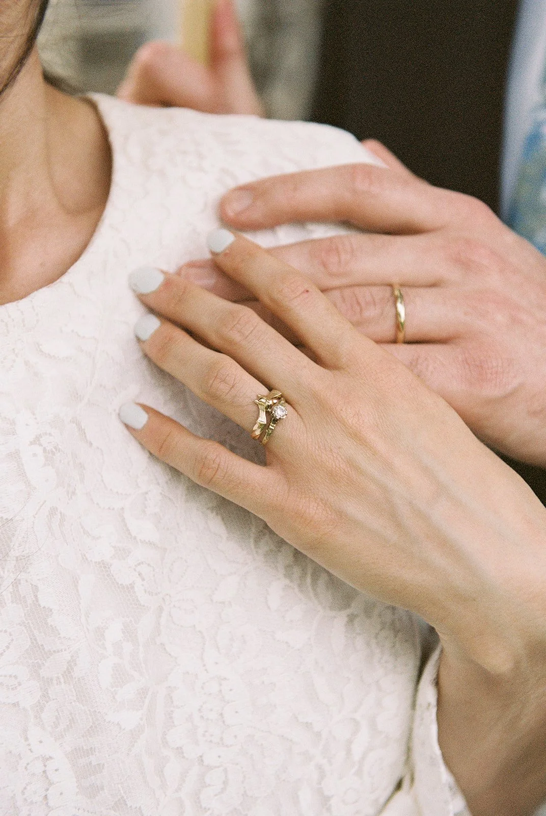 Close up shot of a bride and groom holding hands and showing off their wedding rings.