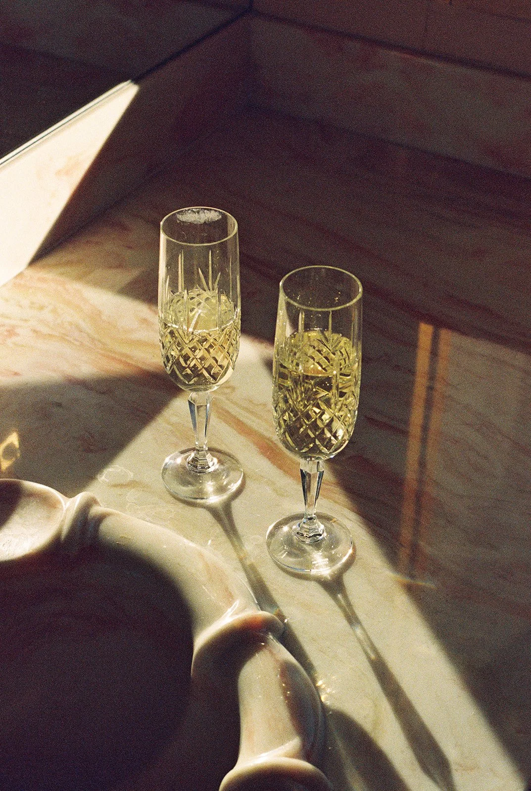 Two glasses of champagne sitting on the bathroom counter on film.
