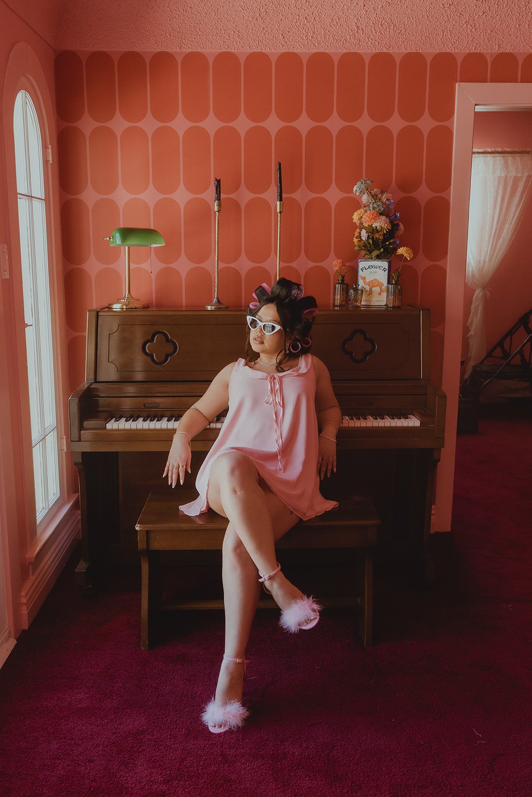 Woman posing on a piano bench inside The Pink Portal Den in Las Vegas.