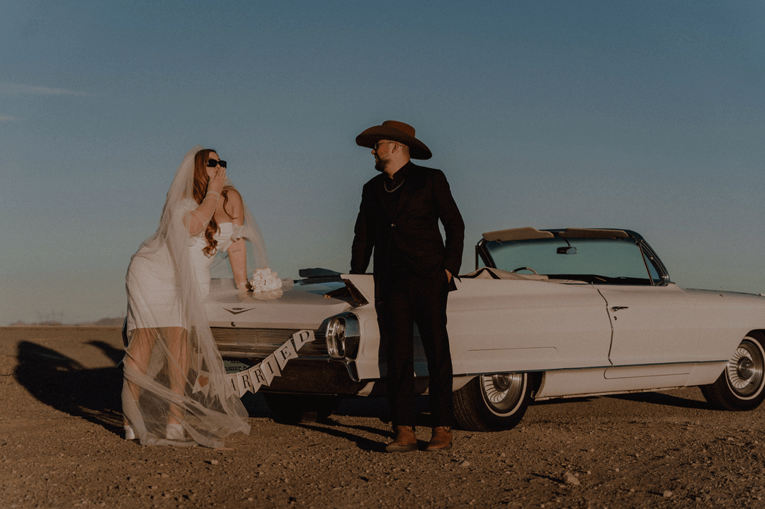 Bride and groom in the Las Vegas desert bed during golden hour with a vintage car