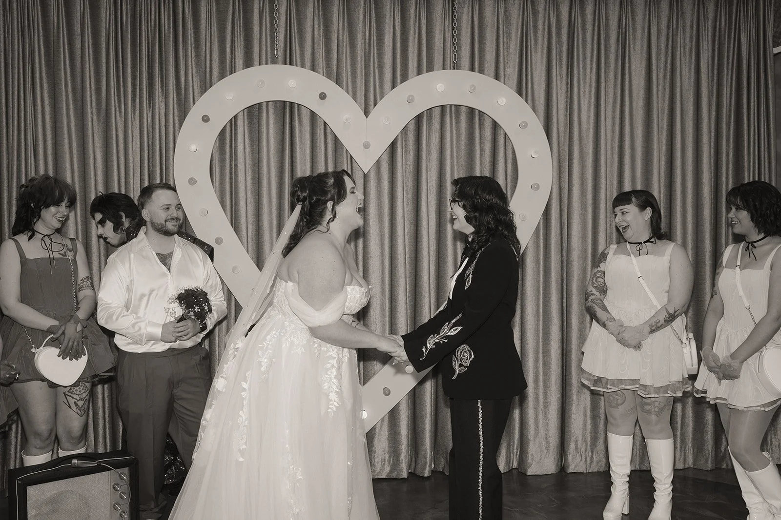 Couple laughing during their Sure Thing Chapel wedding ceremony with their wedding party standing beside them.