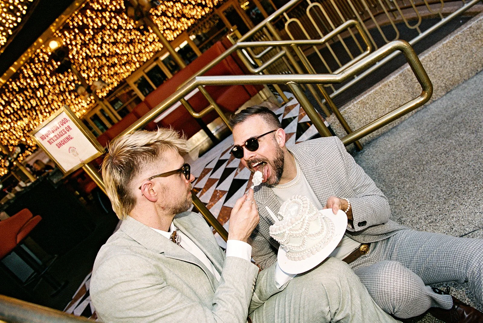 Man feeding his husband cake at Carousel Bar during their all film Las Vegas elopement photos.