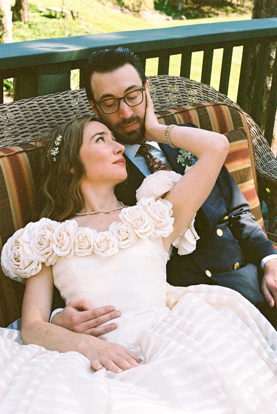 Intimate film wedding portrait of the bride and groom relaxing together on a wicker sofa at Deer Mountain Inn.