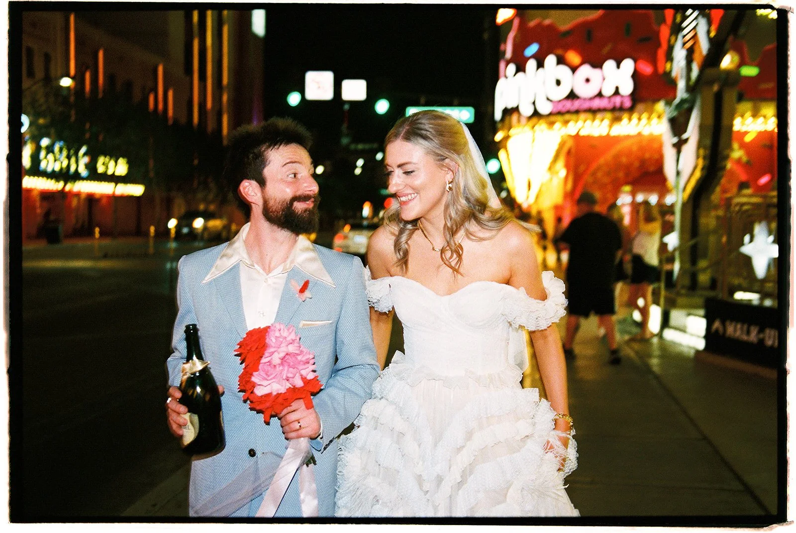 Bride and groom walking down Fremont Street during their Las Vegas elopement photos on 35mm film.