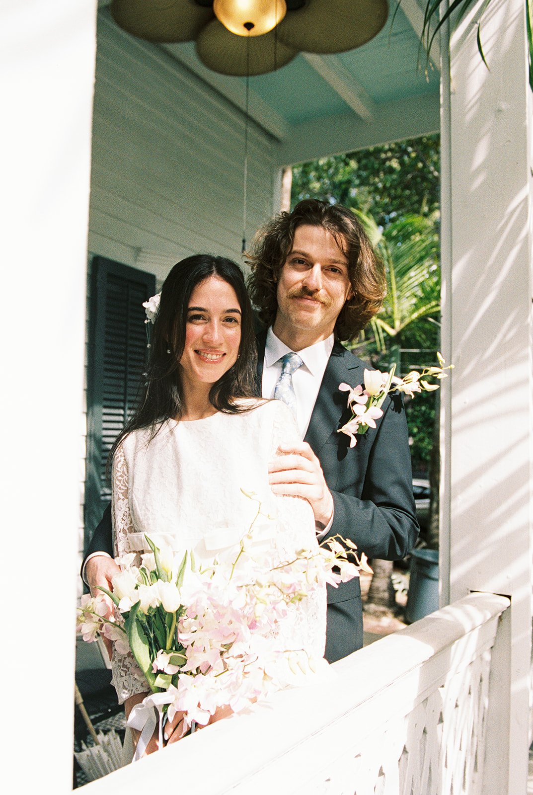 Bride and groom posing together on the open porch at Old Town Manor in Key West, Florida.