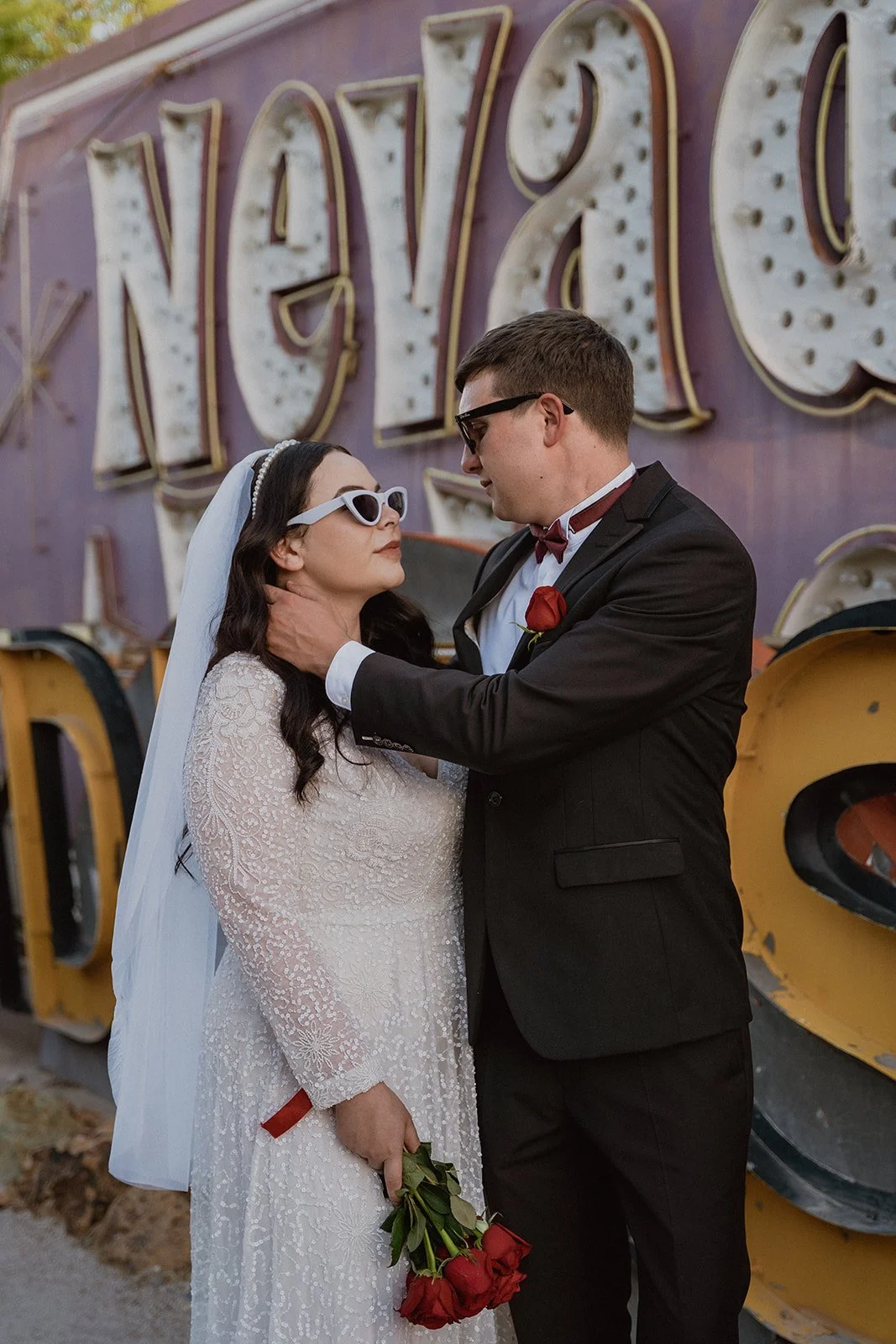 Bride and groom posing in front of a vintager sign that says Nevada.