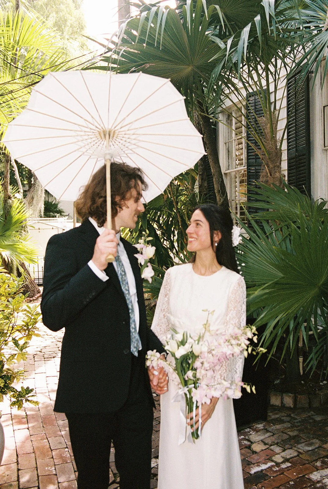 Bride and groom walking the pathways at Old Town Manor in Key West, Florida for their elopement photos on 35mm film.