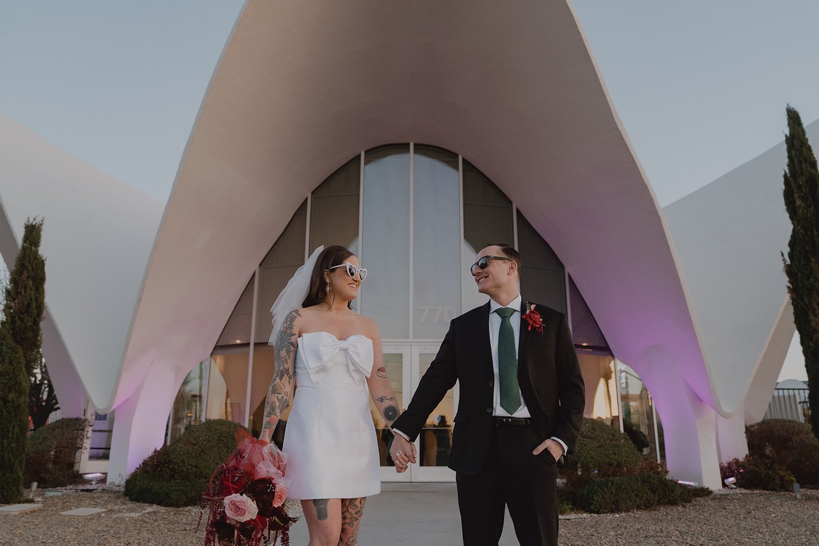Bride and groom holding hands and looking at one another in front of the Neon Museum in Las Vegas.