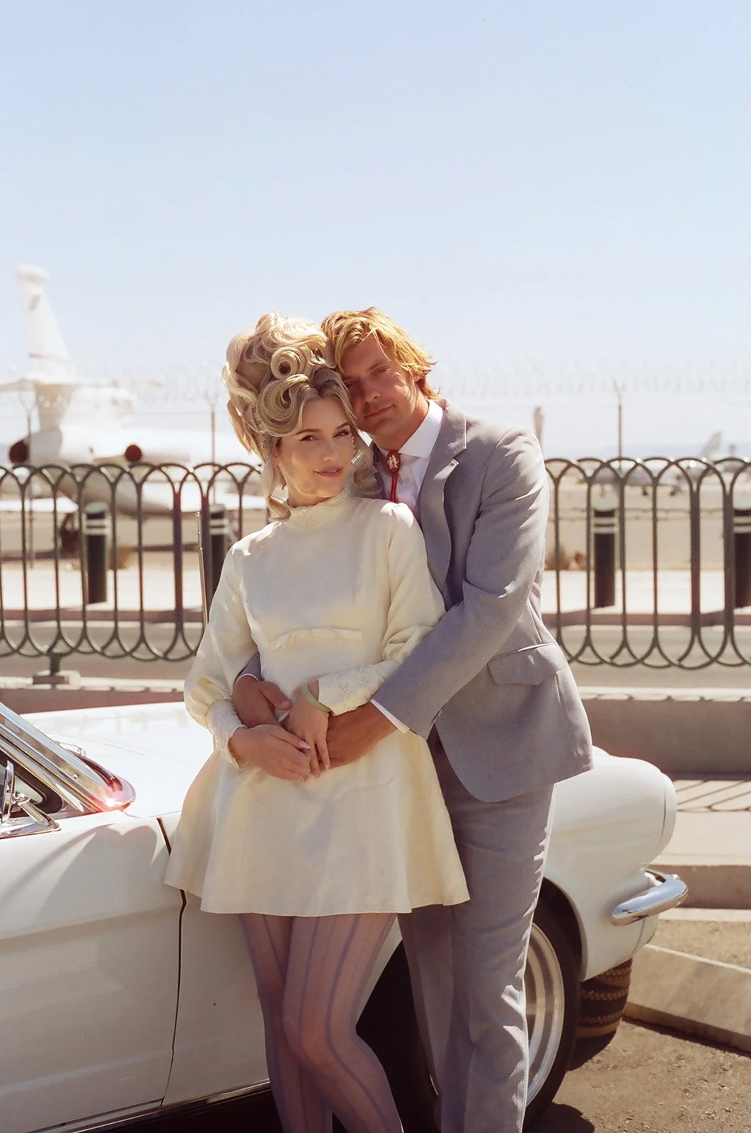 Couple posing next to their classic car from 777 Exotics for their vintage Vegas wedding photos.