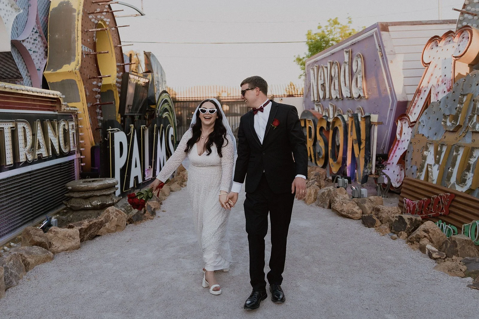 Bride and groom walking through The Neon Museum for their Las Vegas wedding portraits.
