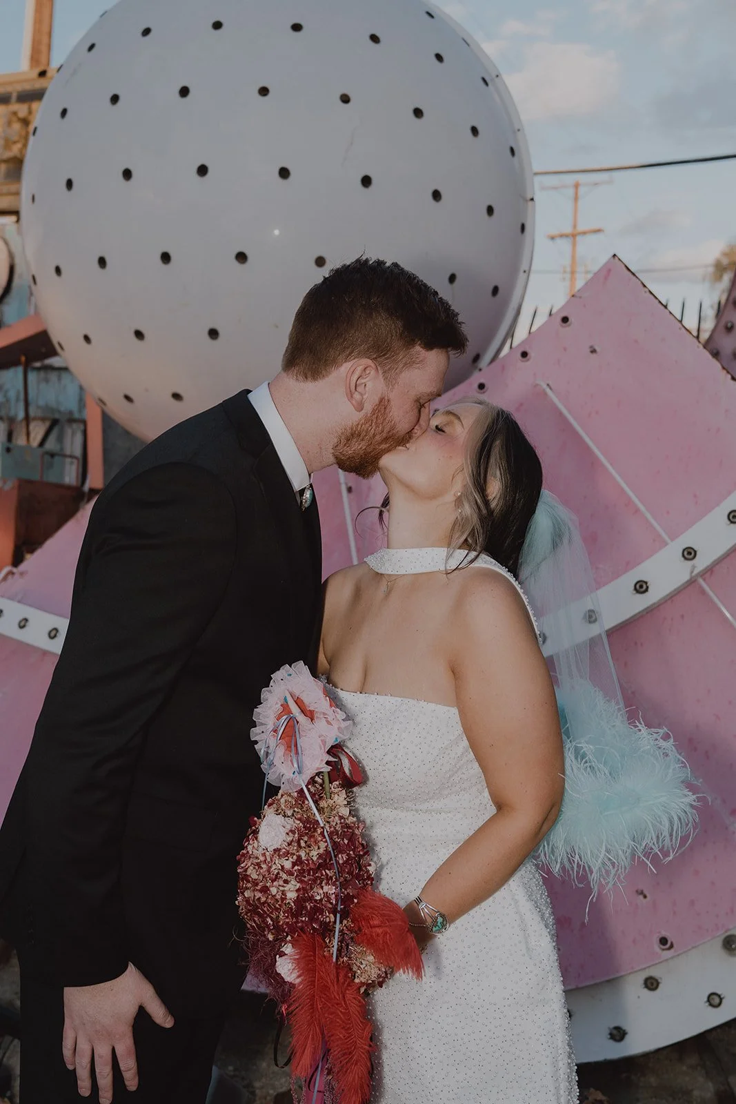 Bride and groom kissing in front of colorful art at The Neon Museum in Las Vegas.