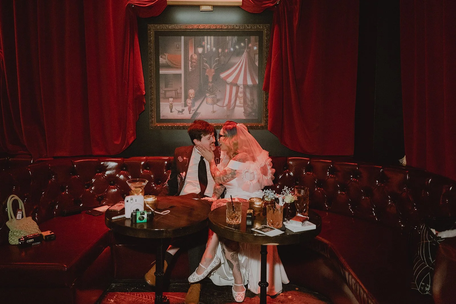Bride and groom sitting together in red booth at Cheapshot Las Vegas wedding reception.