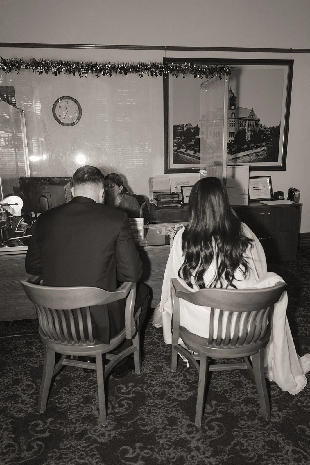 Black and white photo of a bride and groom checking in for their Old Orange County Courthouse wedding in Santa Ana, California.