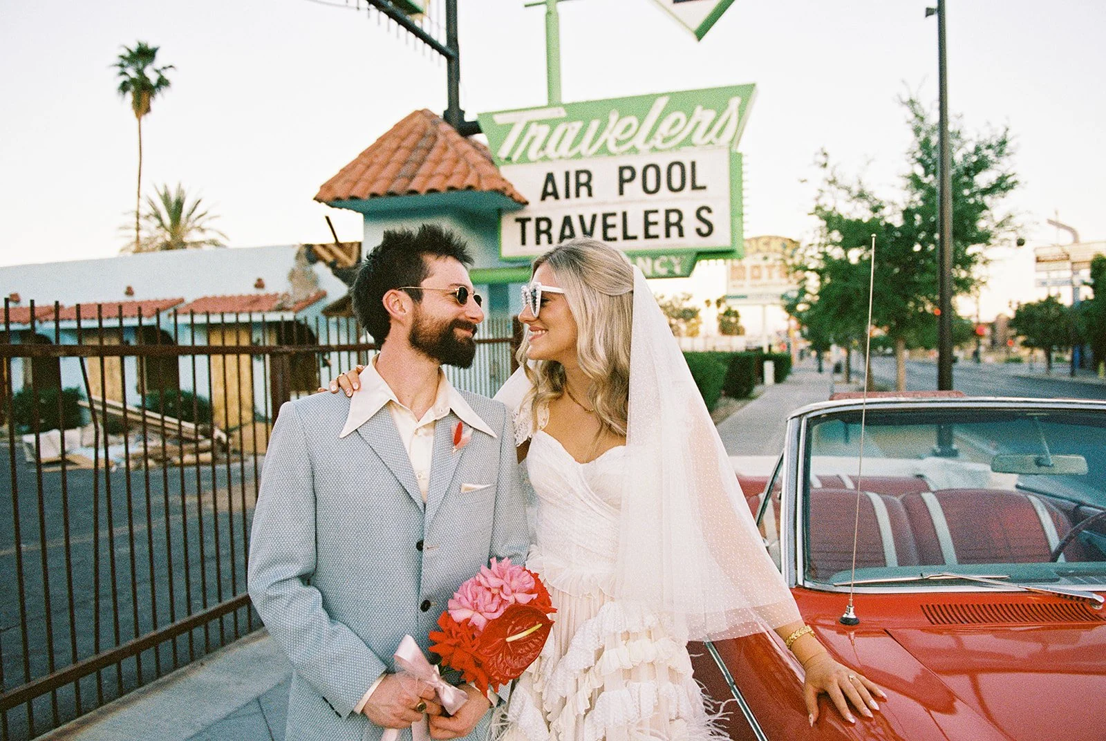 Couple posing next to the red convertible outside of Sure Thing Chapel on 35mm film.