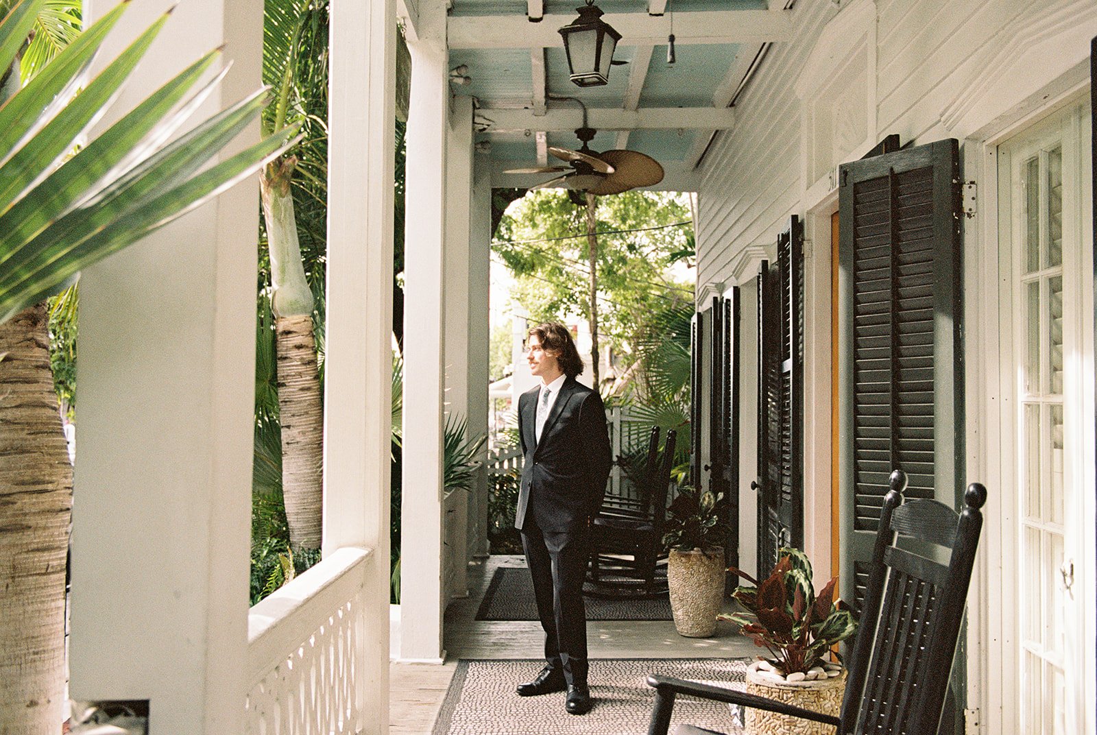 Groom standing on the porch at Old Town Manor in Key West, Florida during a 35mm film elopement.