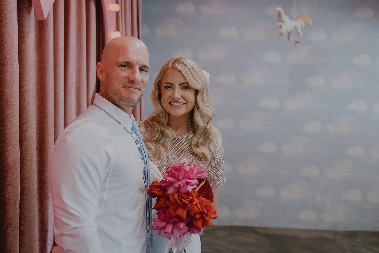 Newlyweds posing together inside Sure Thing Chapel with the heart backdrop and ceremony space visible.