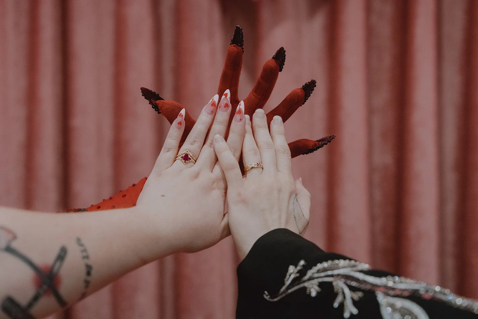 Couple showing off their wedding rings with Hellvis' claws behind their hands from a Sure Thing Chapel wedding in Las Vegas.