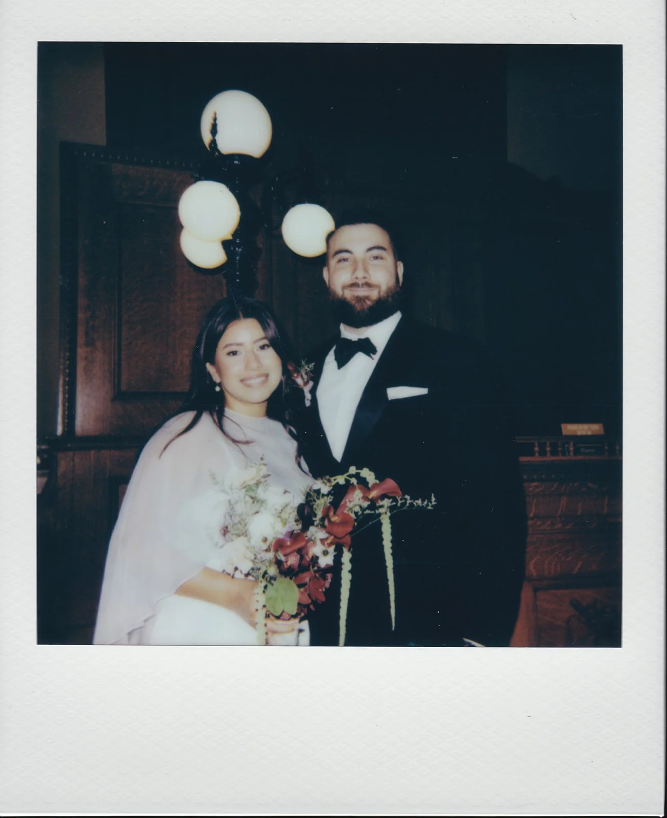 Polaroid photo of a bride and groom posing in the courtroom at Old Orange County Courthouse in Santa Ana, California.