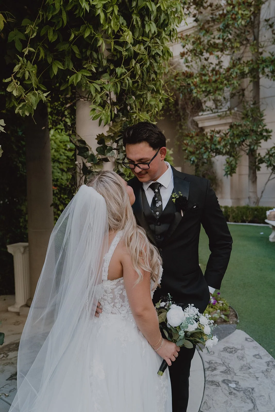 Close-up portrait of the bride and groom framed by greenery during their Caesars Palace Venus Garden wedding.
