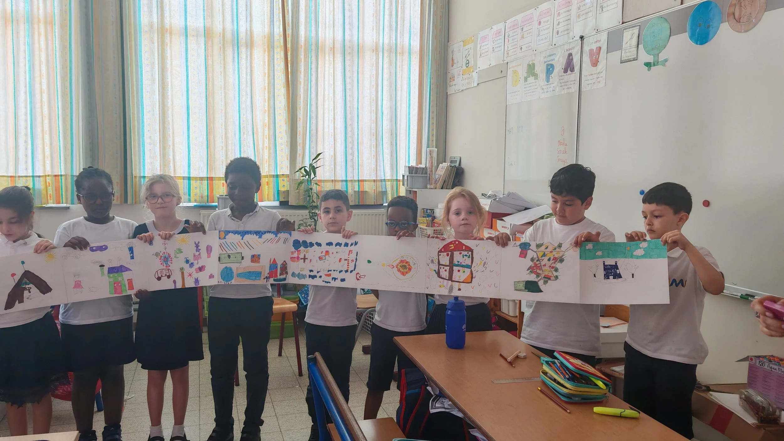 Groupe d'enfants à l'école, tenant une bannière avec des dessins colorés.