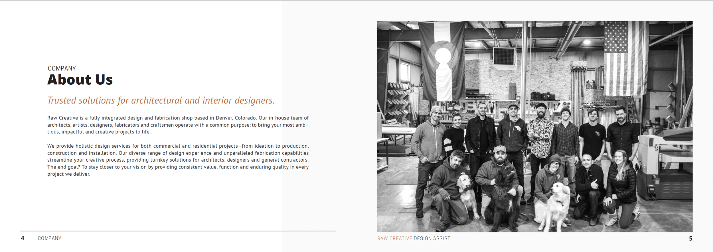 Black and white photo of a group of people in a workshop or studio, some with dogs, with flags hanging in the background and various tools and equipment around.