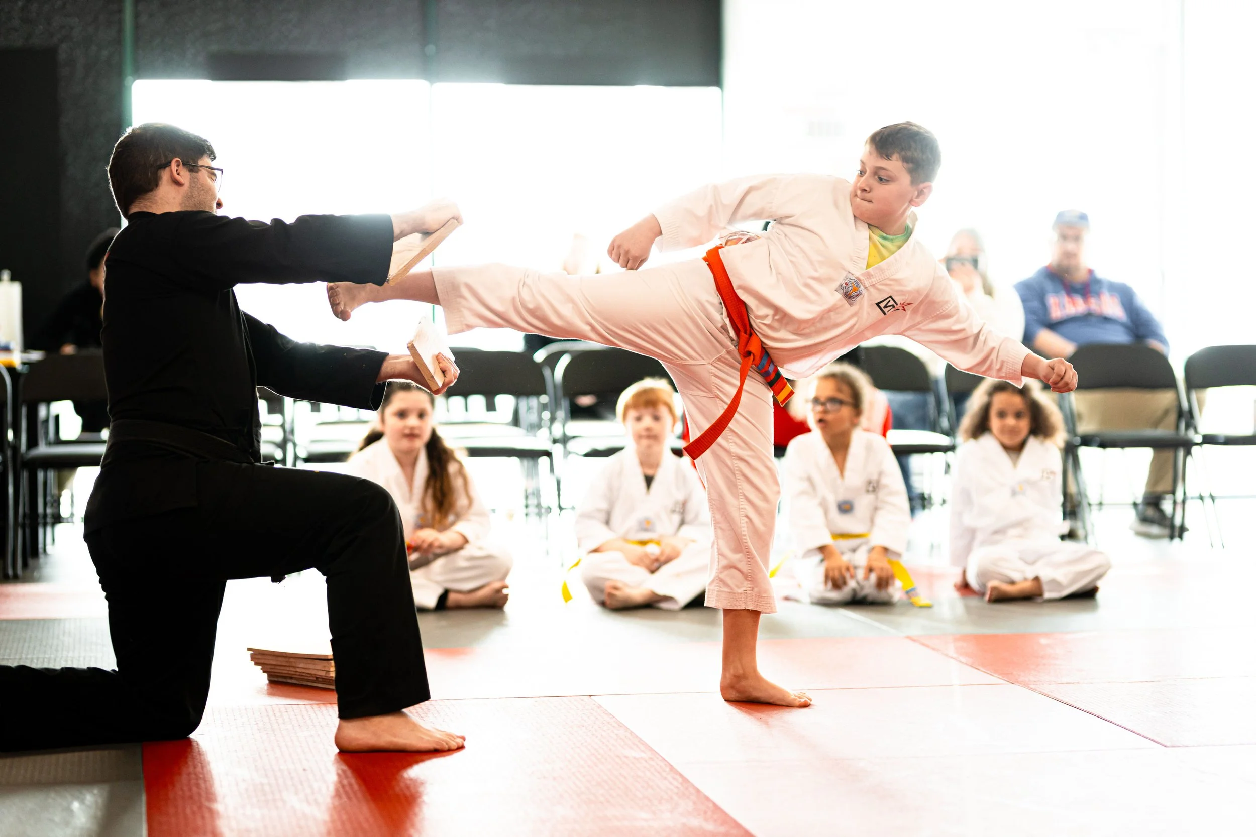 Vertical Taekwondo Lees Summit Sutdent breaks a karate board with a powerful kick