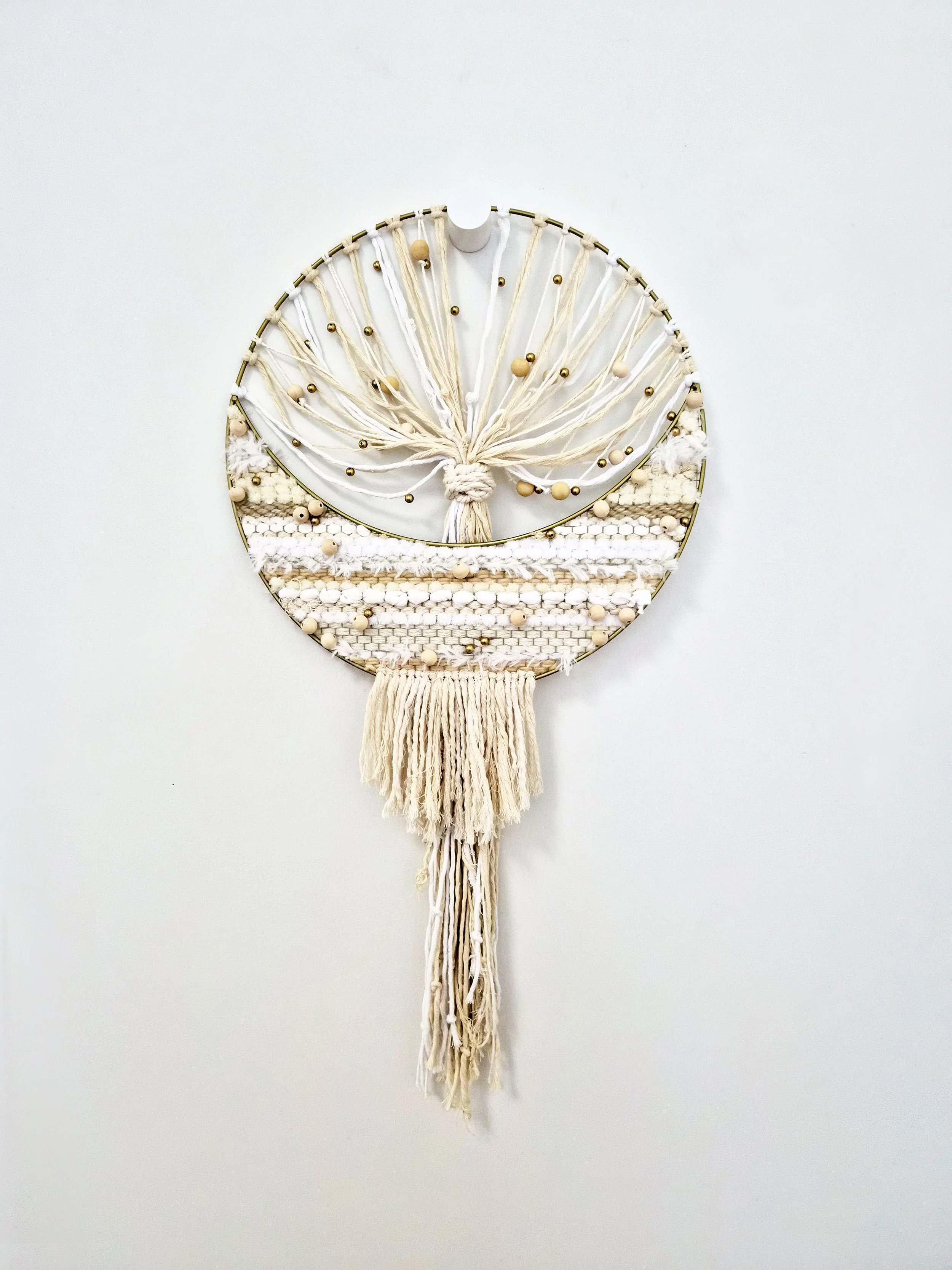 A fiber art piece comprised of interwoven fibers and beads within a metallic mesh moon