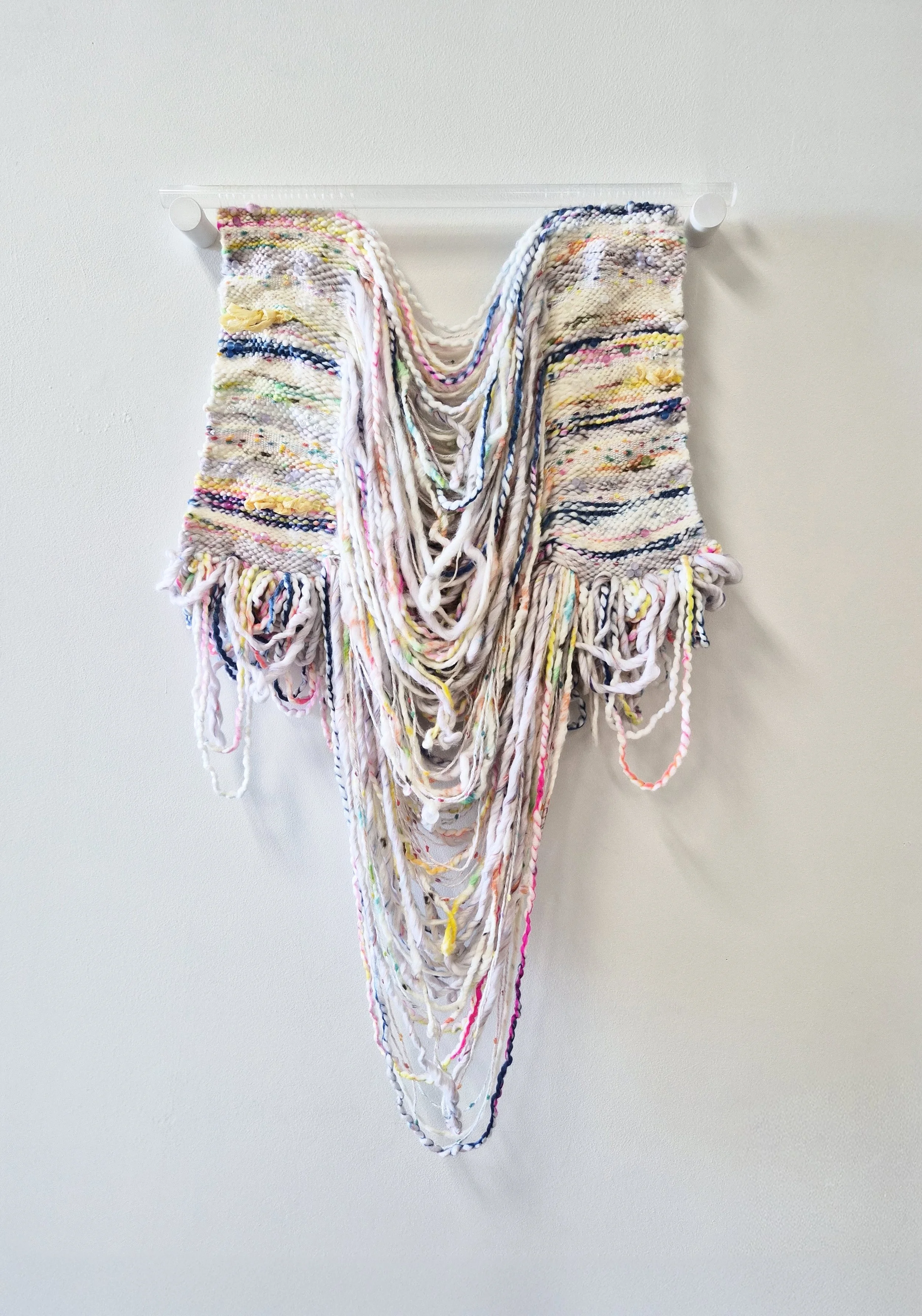 A composition of interwoven fibers, beads, and paper suspended from a translucent acrylic dowel