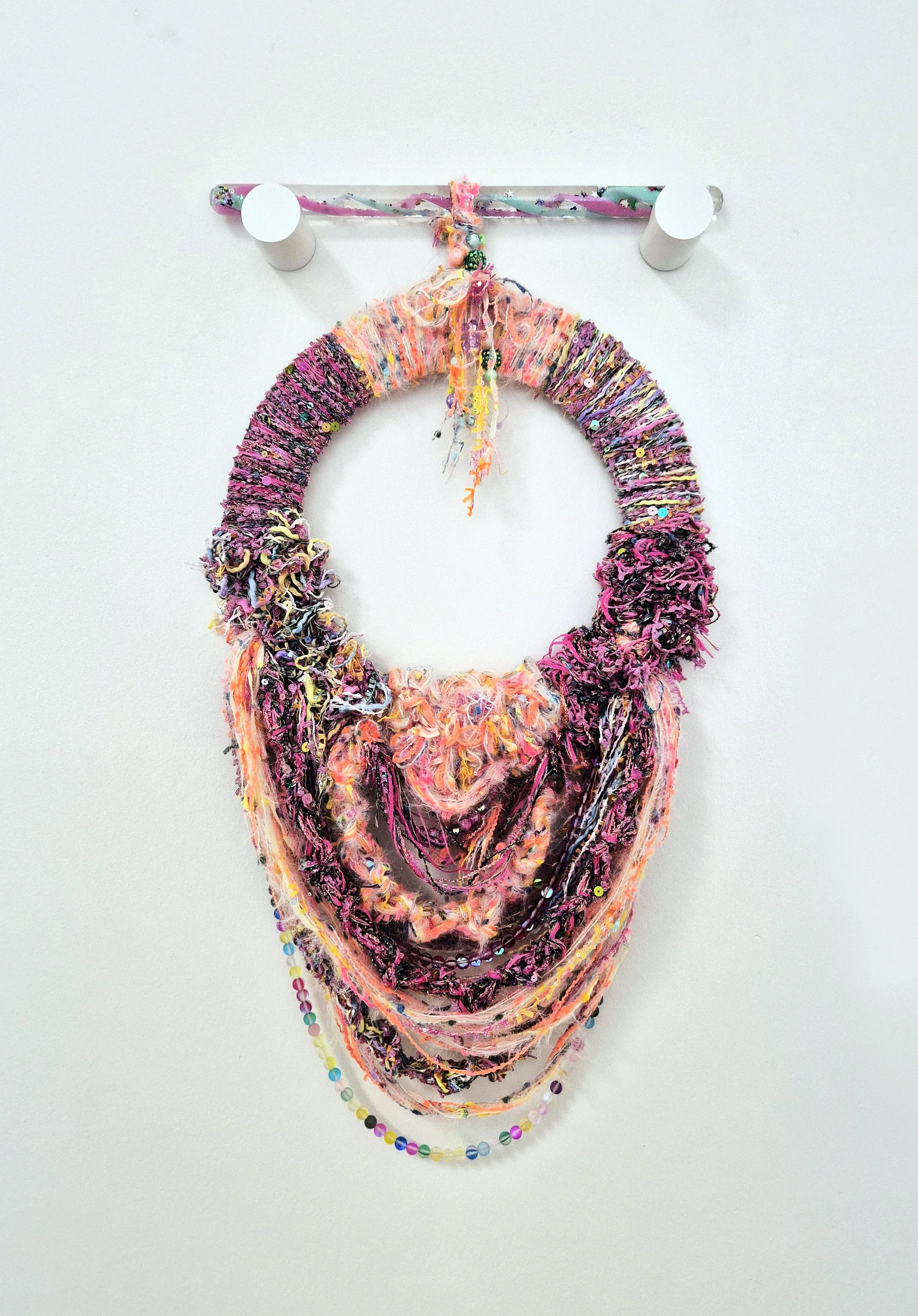 A fiber art piece comprised of interwoven fibers and beads suspended from a translucent sensory wand