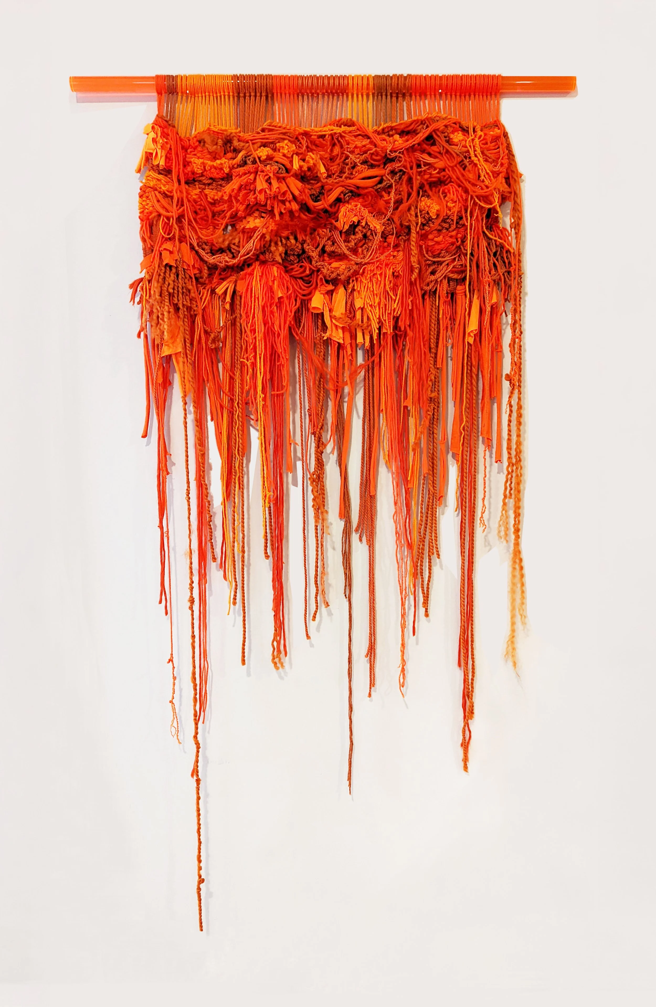 A fiber art piece comprised of interwoven fibers suspended from a translucent acrylic dowel